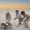 Friends and family roasting marshmallows at a private beach bonfire in Miramar Beach