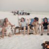 Friends laughing and relaxing around a private beach bonfire in Miramar Beach